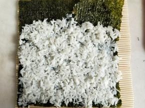 米饭用勺子背面按压铺平，上面留约3厘米左右不铺。
