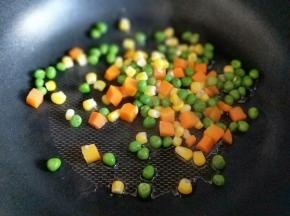 起油锅，加入焯水的玉米粒，胡萝卜丁，豌豆煸炒。