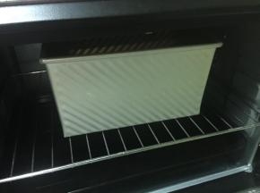 烤箱底部放烤盘，倒进开水，把吐司盒放在中层，进行二次发酵。参考温度38°，60分钟。