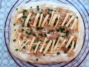 面团翻面整理一下，依次铺上沙拉酱，肉松，芝士片和香葱叶