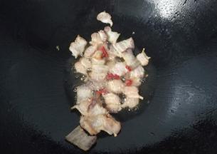 锅中入少许油，下腊肉煸炒至稍微焦黄出油后再加少许干红辣椒煸香；
