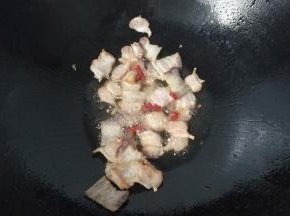 锅中入少许油，下腊肉煸炒至稍微焦黄出油后再加少许干红辣椒煸香；