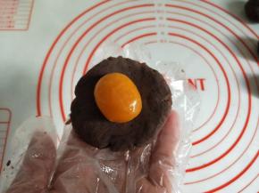 取一份豆沙按扁，包入一个咸蛋黄。