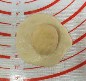 取一个水油皮按扁，包入一个油酥包好。