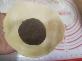 包入一个蛋黄豆沙馅，收口朝下放入烤盘。