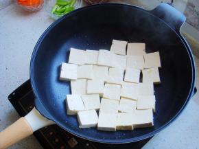 把豆腐块摆放入锅内中火开始煎。