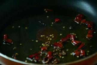 锅中倒入适量的菜籽油，等油熟烫之后关火，下入干辣椒，花椒翻炒，开小火继续炒香关火。