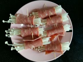 把金针菇分成均匀的几份，用培根卷起来，用牙签固定。培根的长度长一些，这样卷起来才不容易掉。