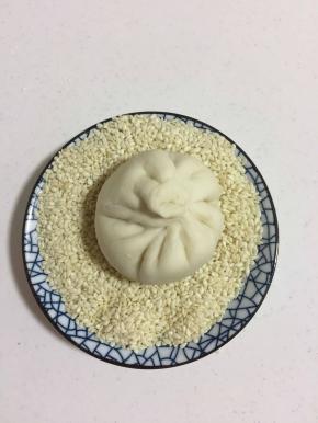 放进装白芝麻的碗里，使小笼包底部均匀的沾满白芝麻。