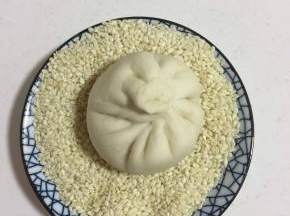 放进装白芝麻的碗里，使小笼包底部均匀的沾满白芝麻。