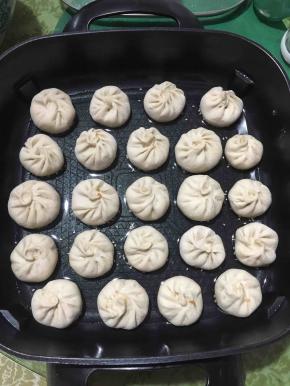 锅里先放油，把底部沾满白芝麻的小笼包放进锅里，开火煎一分钟左右。