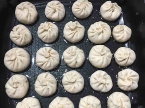 锅里先放油，把底部沾满白芝麻的小笼包放进锅里，开火煎一分钟左右。
