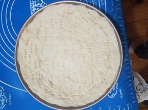 面团放入披萨烤盘均匀摊平后用叉子插满小孔。