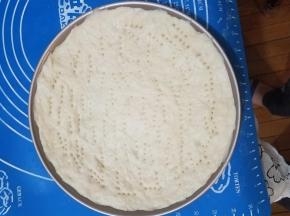 面团放入披萨烤盘均匀摊平后用叉子插满小孔。
