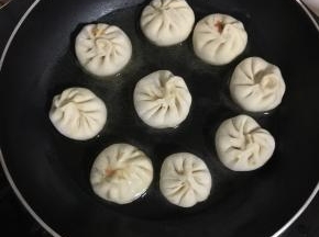 放入包好的迷你小笼包，调小火煎一分钟左右！底部煎至微黄即可！