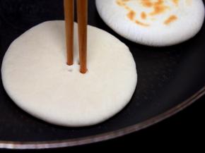 接下来将平底锅烧到微热（不用油），下小饼生坯烙制，用一双筷子扎4个小眼，称菊花心。