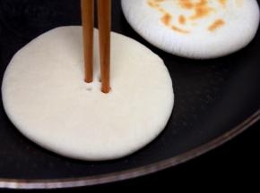 接下来将平底锅烧到微热（不用油），下小饼生坯烙制，用一双筷子扎4个小眼，称菊花心。