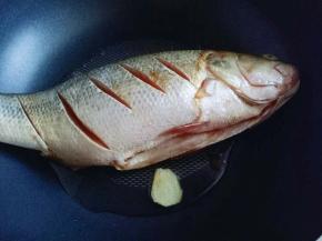 锅中加入油，放入姜山，再放入腌制好的鲈鱼，煎至两面微黄盛出。