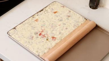 擀面杖把表面擀平，同时注意右边用辅助工具把牛轧糖体压紧。整理好四边和平面放凉等待脱模吧