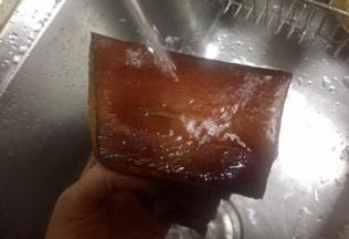 同时用热水洗腊肉用刀在腊肉表面刮出熏了的碳层，腊肉露出诱人焦黄的颜色