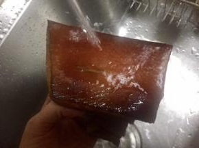 同时用热水洗腊肉用刀在腊肉表面刮出熏了的碳层，腊肉露出诱人焦黄的颜色