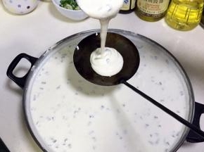 待油温加热超过180度时，从锅内取出油饼勺，往油饼勺内倒入一勺豆米浆。