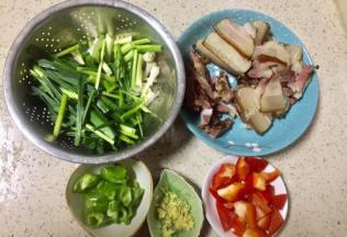 煮腊肉的时候把蒜苗洗净后切段，径和叶要分开放，青椒和红椒切小块，老姜切姜米，腊肉如有单独的瘦肉和大块肉分开放