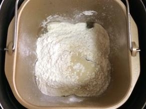 在面包机桶内加入温水、面粉和酵母粉，启动和面程序。
