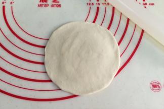 取一份面团，用擀面杖擀成中间厚周围薄的圆面皮。