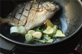把鱼推到一边，用余油炒香葱姜蒜和香菜根。