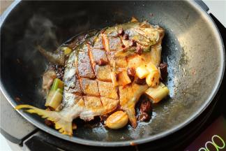 鱼再翻面个煎一会，使酱料裹满鱼身，煎入味。