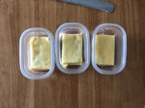 把蛋糕切割为和盒子一样大小的长方形片，先放一片蛋糕在盒子底部