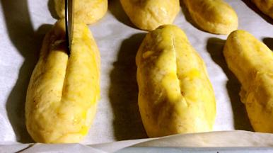 将蛋黄液刷在面包坯上，在用刀在面包坯中间划一刀