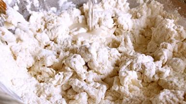 将清水慢慢加入到高筋面粉里，边加水边搅拌成絮状