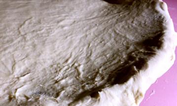 将擀好的饼皮铺在披萨盘上