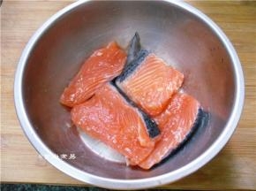 端起盆子反复抛起鱼块，让食盐均匀渗透鱼肉中，腌制片刻