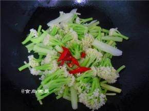 倒入花菜和辣椒段翻炒片刻、太干时撒少许清水，让菜受热均匀、色泽好看