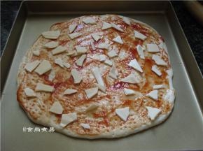 面饼上面涂抹一层番茄酱、撒些马苏里拉芝士碎