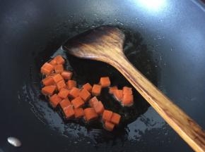 锅里热油后放入胡萝卜粒炒香