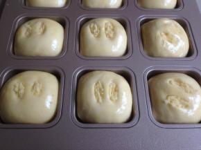 在面包坯表面涂上全蛋液，在割口里，塞入一点椰蓉馅