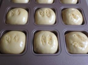 在面包坯表面涂上全蛋液，在割口里，塞入一点椰蓉馅