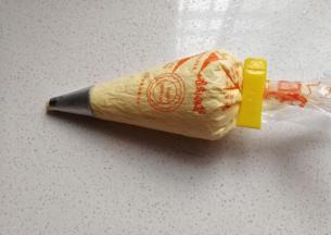 然后把拌好的蛋糊装入有圆形裱花嘴的裱花袋中，要预留一点蛋糕哦；