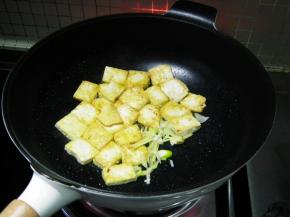将豆腐推在锅的一边后加入葱姜爆香。
