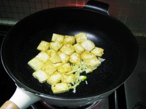 将豆腐推在锅的一边后加入葱姜爆香。