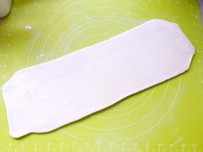 再撒点干粉，将对折好的面片擀成长条，长度比之前擀的短一些，可以折三折即可