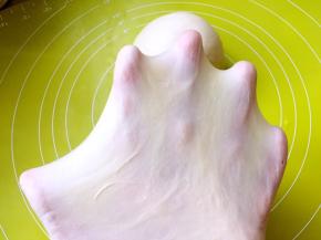 黄油跟面团揉均匀后，切下一小块面团，双手慢慢撑开，可以撑出手套膜即可