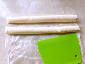 将不烫手的奶酪糊均分，装入两个保鲜袋，我用的大号保鲜袋，再用刮板将奶酪糊推至保鲜袋底部，形成均匀的长条