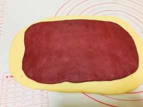 发酵好后，将主面团擀成片，带颜色的面团也擀成片，覆盖到主面团的面片上。拍掉周边的气泡。轻按几下。