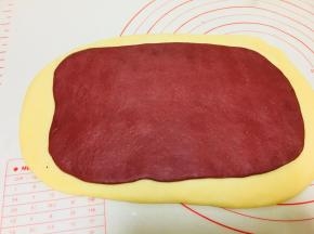 发酵好后，将主面团擀成片，带颜色的面团也擀成片，覆盖到主面团的面片上。拍掉周边的气泡。轻按几下。