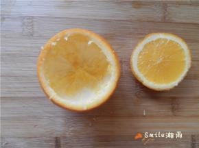 用一个不锈钢勺子，把橙子里面的果肉给挖出来，留下完整的球形橙子皮容器及其小盖子。